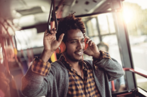 A man with headphones on his ears is smiling.