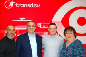 A group of people standing in front of a red wall.