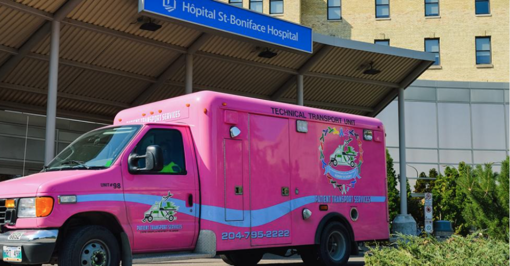 A pink ambulance parked in front of an hospital.